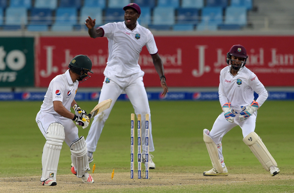 West Indies' captain Jason Holder (C) and wicketkeeper Shai Hope (R) celebrate after bowling out Pakistani batsman Mohammad Nawaz (L) on the fourth day of the first day-night Test between Pakistan and the West Indies at the Dubai International Cricket Sta