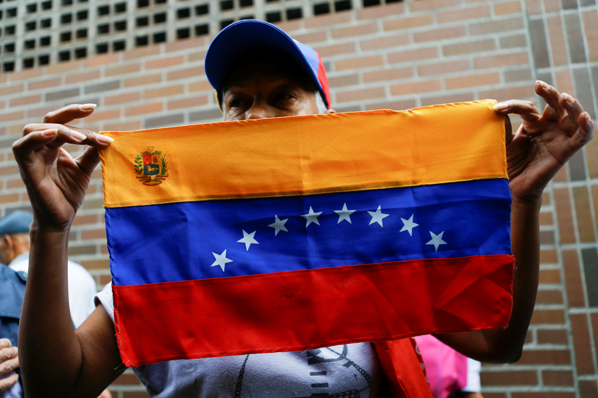 A woman holds a Venezuelan flag outside a validation center in Caracas, Venezuela, June 20, 2016.( REUTERS / Ivan Alvarado) 