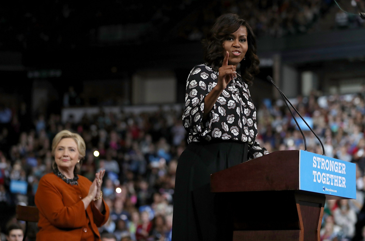 Democratic presidential nominee former Secretary of State Hillary Clinton (L) looks on as First Lady Michelle Obama speaks during a campaign rally at Wake Forest University on October 27, 2016 in Winston-Salem, North Carolina. With less than two weeks to 