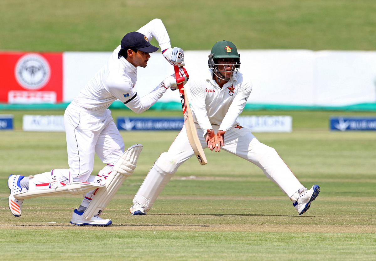 Sri Lanka batsman Dhananjaya de Silva (L) is in action as Brian Chari escapes a ball during the first day of the second cricket Test match between Sri Lanka and hosts Zimbabwe at the Harare Sports club, on November 6, 2016. (AFP / Jekesai Njikizana)