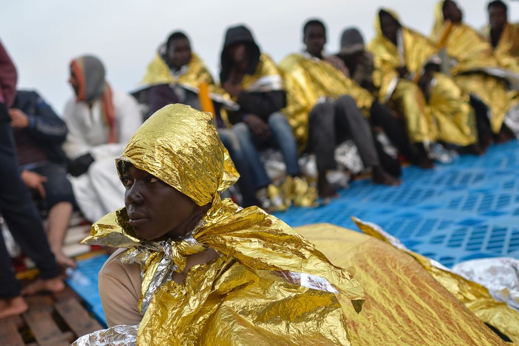 Migrants and refugees wrapped in survival foil blankets relax, aboard the Topaz Responder ship, run by Maltese NGO Moas and the Red Cross, on November 6, 2016 after a rescue operation off the Libyan coast in the Mediterranean sea. / AFP / ANDREAS SOLARO