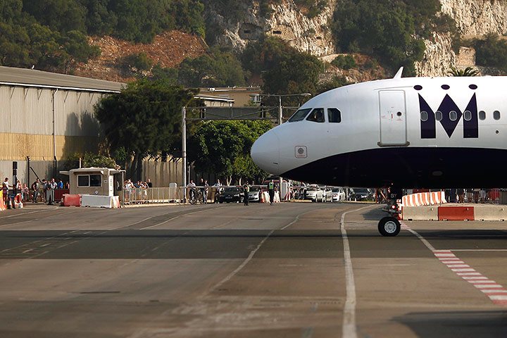 Pedestrians and drivers wait to cross the road of the Gibraltar international airport as an aircraft taxis on the tarmac, August 2013, (Reuters / Jon Nazca)