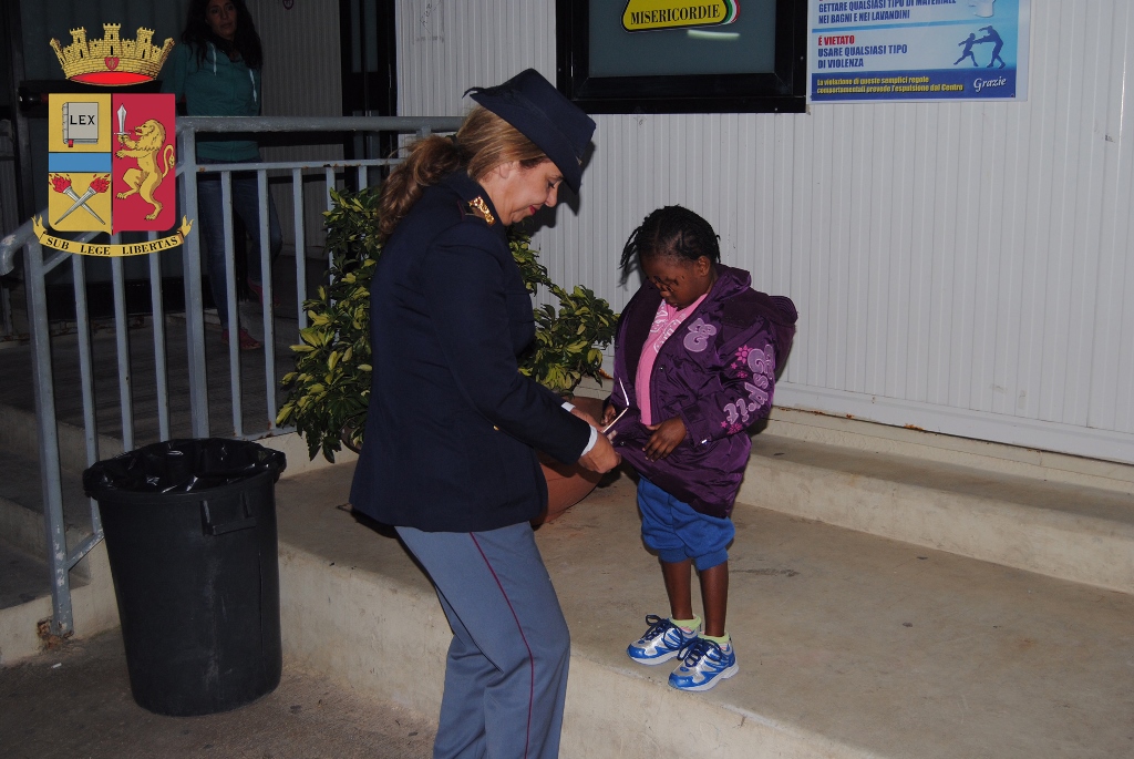 This handout picture released by the Italian police (Polizia di Stato) on November 23, 2016, shows police officer Maria Volpe taking care of Oumoh, 4, a young Ivoirian migrant arrived on November 5, 2016 in Lampedusa. AFP / Polizia di Stato - Italian Poli