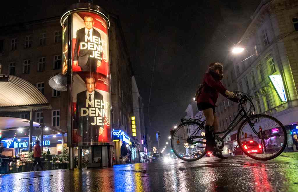 A woman cycles past posters of presidential candidate Alexander Van den Bellen,independent candidate and the former chief of the Green party in Vienna, Austria on November 26, 2016. AFP / JOE KLAMAR