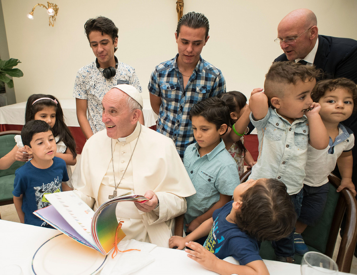 Pope Francis reading a book to Syrian refugee children at  Vatican (AFP) 