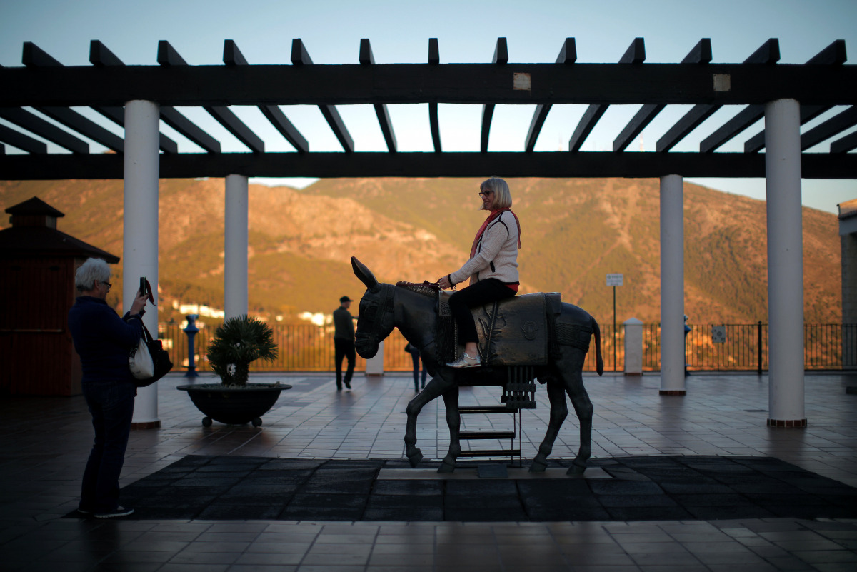 British women take photos of themselves with a statue of a burro taxi (donkey taxi) during their holidays in Mijas, near Malaga, southern Spain, November 15, 2016. Picture taken November 15, 2016. REUTERS/Jon Nazca