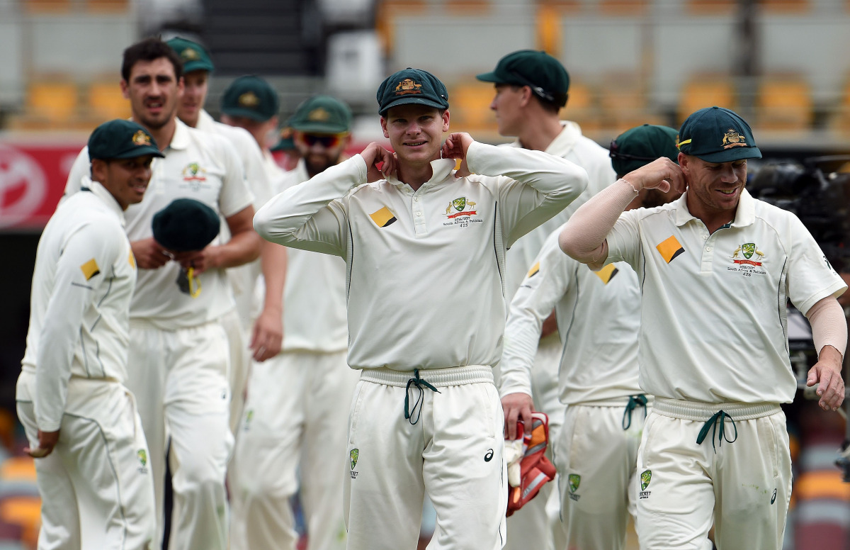 Australia's captain Steve Smith (C) adjusts his collar as he walks off the field with teammates after beating Pakistan in the first day-night cricket Test match between Australia and Pakistan in Brisbane on December 19, 2016. (AFP / Saeed KHAN)