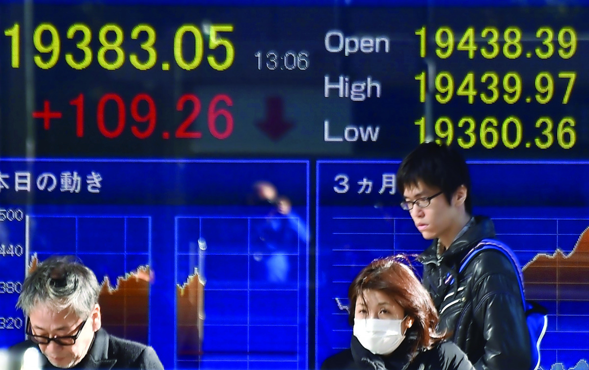 Pedestrians walk past an electric quotation board of the Nikkei key index in Tokyo. 