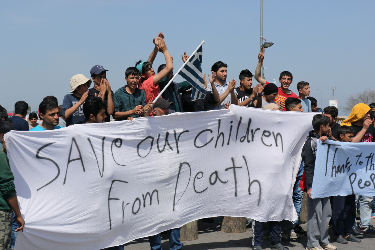 Refugees hold banners and block the highway which connects Greece and Macedonia as they stage a protesin the Idomeni town of Greece on April 5, 2016 (Anadolu Agency / Besar Ademi) 
