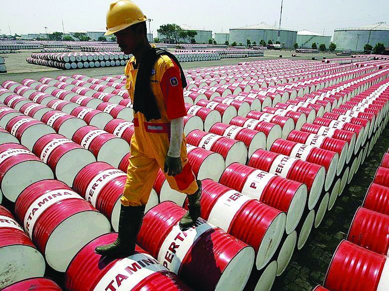 A worker walks over the barrels of crude oil at an inventory facility.