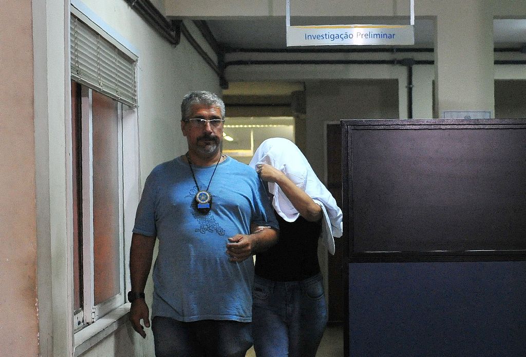 A Brazilian civil policeman escorts the wife of Greece's ambassador to Brazil Kyriakos Amiridis, Francoise de Souza Oliveira, who murdered him in a plot hatched with her police officer lover, who confessed to the crime, on December 30, 2016 in Rio de Jane