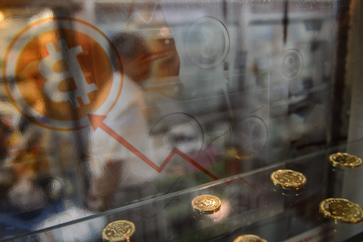This file photo taken on August 3, 2016 shows a man walking past a display cabinet containing models of Bitcoins in Hong Kong. Bitcoin neared its all-time high on January 5, 2017 with the surging digital currency tipped to become a new safe haven asset as