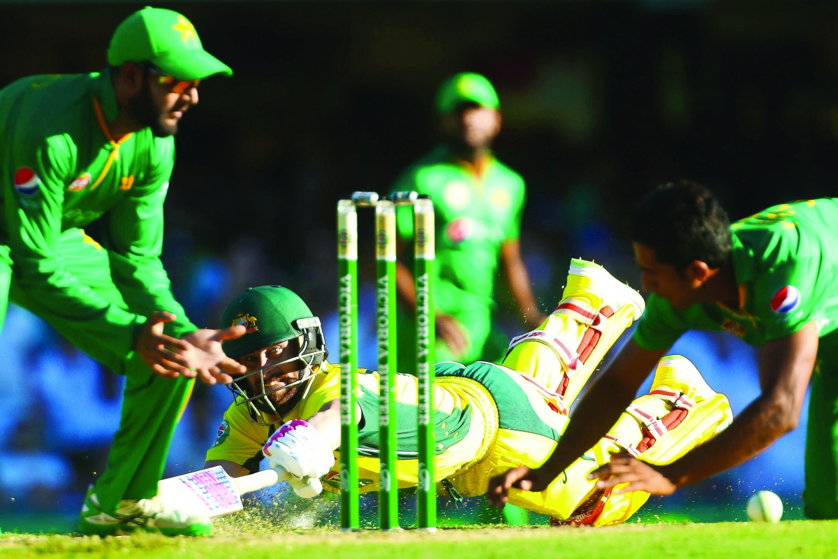 Australian batsman Matthew Wade (centre) dives to make his ground during the one-day international cricket match against Pakistan in Brisbane yesterday. Wade hit a thrilling last-ball century to set up a 92-run victory for Australia.