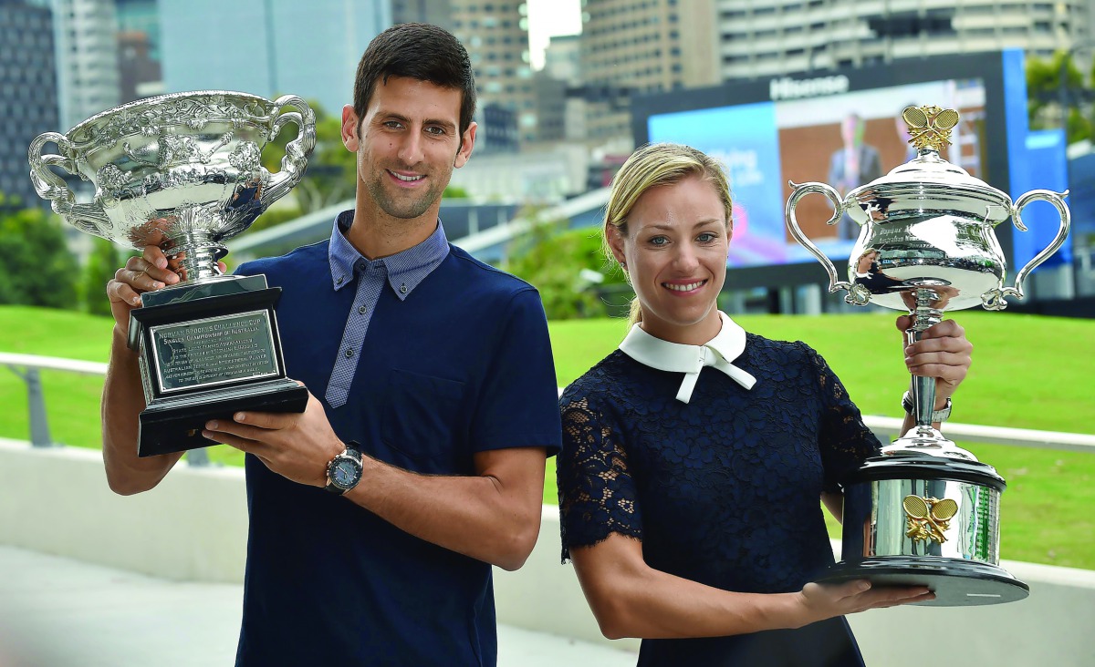 Reigning Australian Open Champions Angelique Kerber of Germany (right) and Novak Djokovic of Serbia carry the trophies ahead of the Australian Open draw ceremony in Melbourne, yesterday.