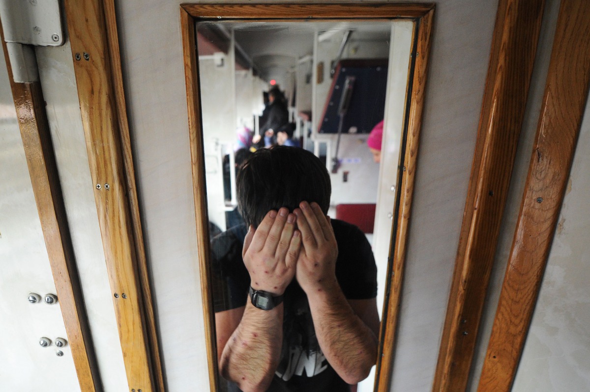 A picture taken in Terespol on December 21, 2016 shows a Chechen man showing scars on his forearms inside a train carriage while returning to the Belarusian city of Brest after a failed attempt to enter Poland. On a snowy day in late December, a commuter 