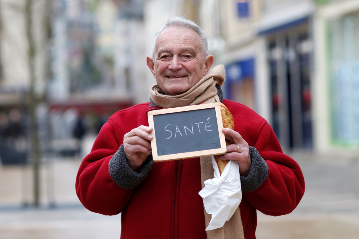 Francois Dore, 83, retired, holds a blackboard with the word 