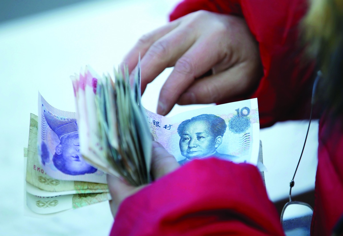 A woman counts Chinese yuan banknotes as she sells tickets for a job fair in Beijing.
