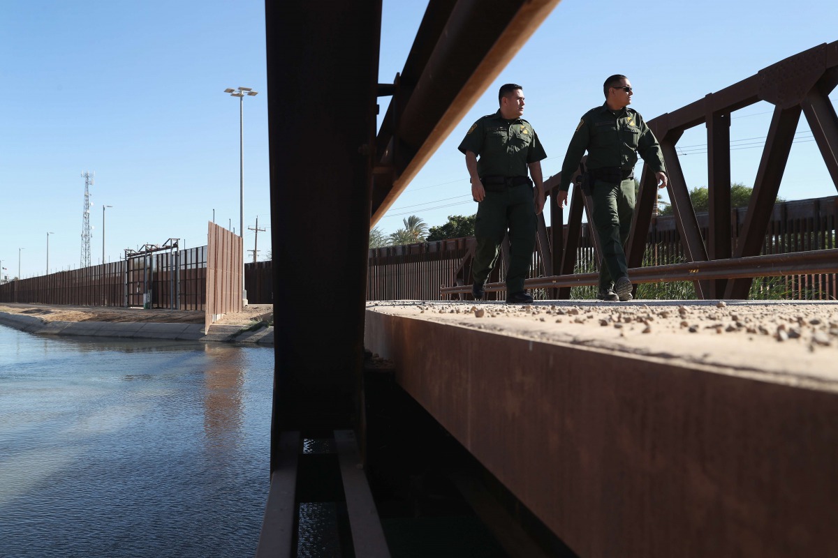 US Border Patrol agents walk over a canal of water flowing into Mexico at the US Mexico border fence on November 17, 2016 in San Luis, Arizona (John Moore / Getty Images / AFP) 