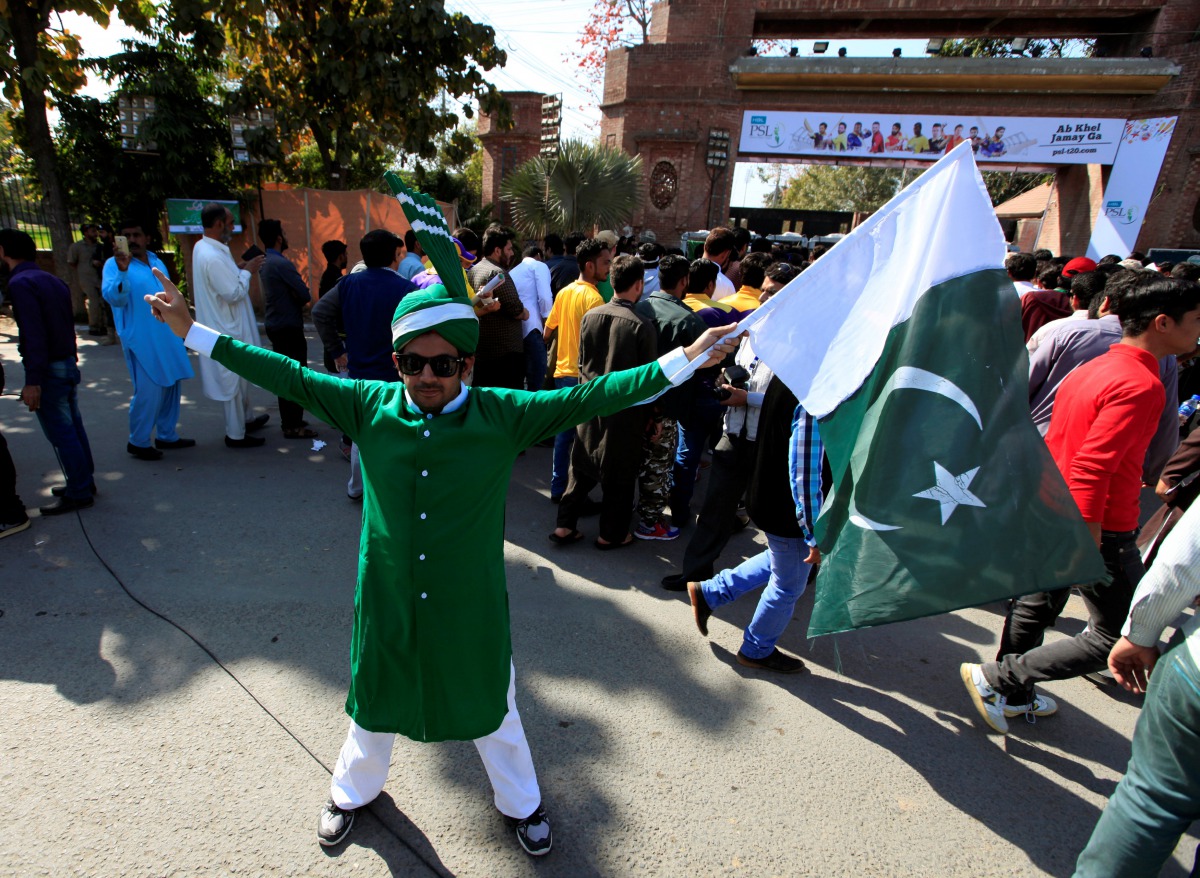 A Pakistani spectator holds a national flag as he waits for his turn to enter Gaddafi Cricket Stadium to watch a hugely anticipated finals of its domestic cricket league, Pakistan Super League (PSL) in Lahore, Pakistan, March 5, 2017. (REUTERS/Faisal Mahm