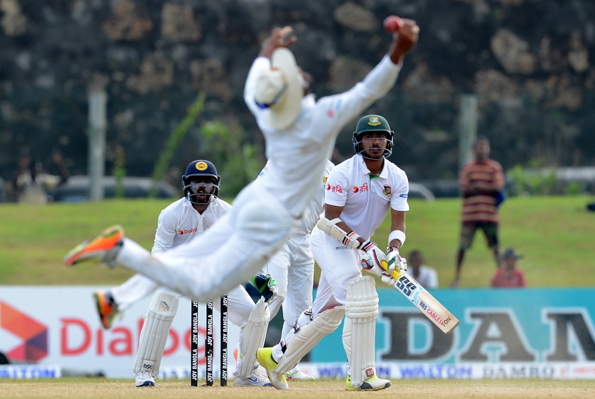 Bangladesh cricketer Soumya Sarkar (R) watches as Sri Lankan cricketer Dinesh Chandimal drops a catch during the fourth day of the opening Test match between Sri Lanka and Bangladesh at the Galle International Cricket Stadium in Galle on March 10, 2017. (