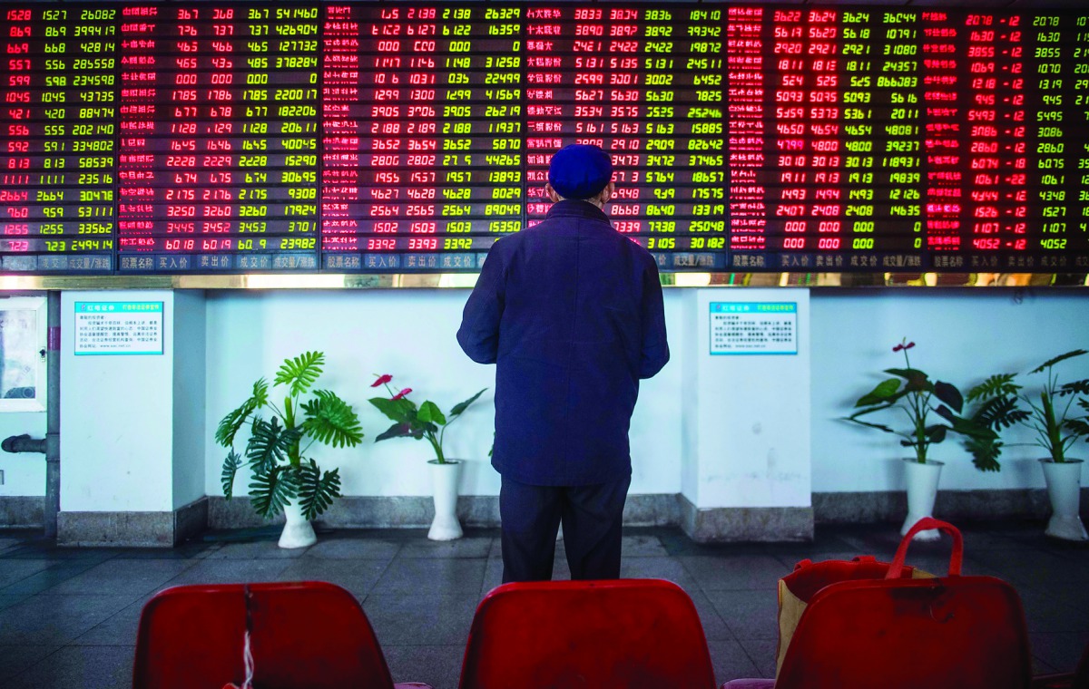 An investor looks at an electronic board showing stock information at a brokerage house in Shanghai.