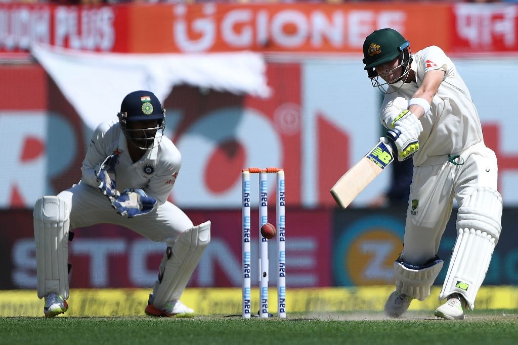 India's wicket keeper Wriddhiman Saha (L) watches as Australia's captain Steve Smith plays a shot during the first day of the fourth and last cricket Test match between India and Australia at the Himachal Pradesh Cricket Association Stadium in Dharamsala 