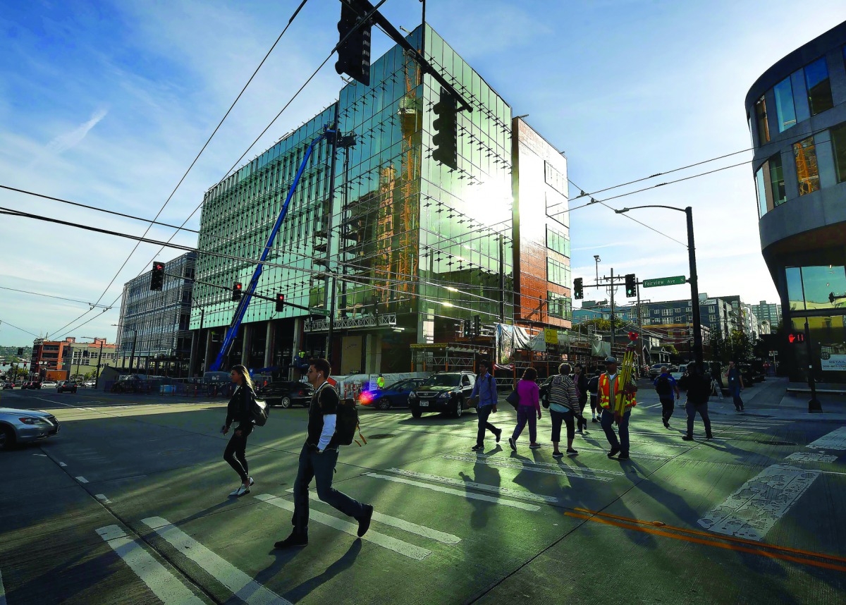 People walk past part of the new Amazon headquarters complex under construction in Seattle, Washington. 