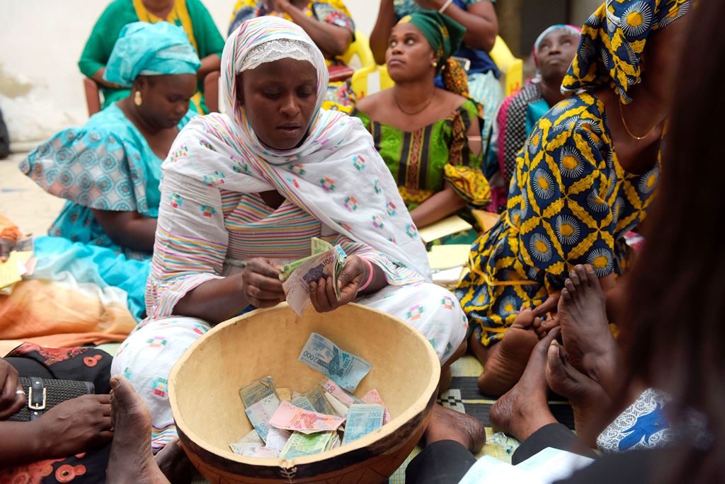 Binta Ndoye sits on a mat in a home in Grand-Mbao, on March 9, 2017, as she counts the money for a 