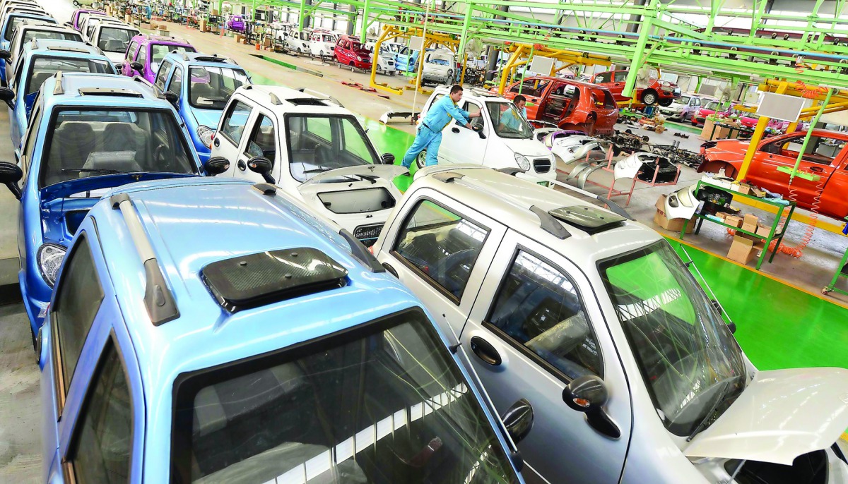 Employees push a newly-assembled electric car to be exported to South America along a production line at an electric vehicle factory in Zouping county, Shandong province of China. 