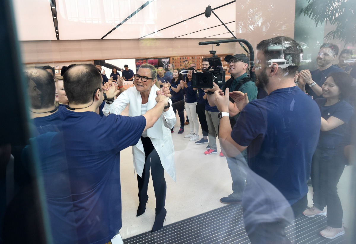 Angela Jean Ahrendts (in white), Senior Vice-President of retail at Apple Inc, greets her employees inside the Apple store in the Orchard shopping district on its opening day in Singapore yesterday. 