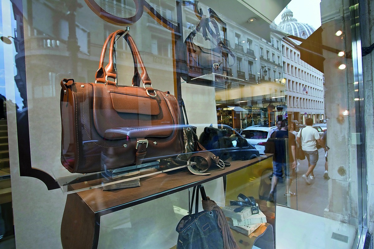 Pedestrians are reflected in the window of a luxury goods store in Paris, France