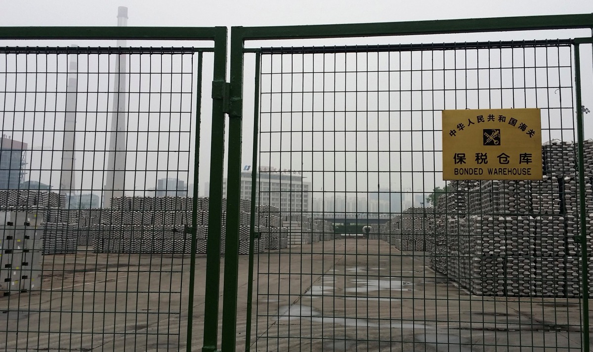FILE PHOTO: Aluminium ingots are seen piled up behind a locked gate of a bonded storage area at the Dagang Terminal of Qingdao Port, in Qingdao, Shandong province June 7, 2014. To match Special Report CHINA-COLLATERAL/FAKE REUTERS/Fayen Wong