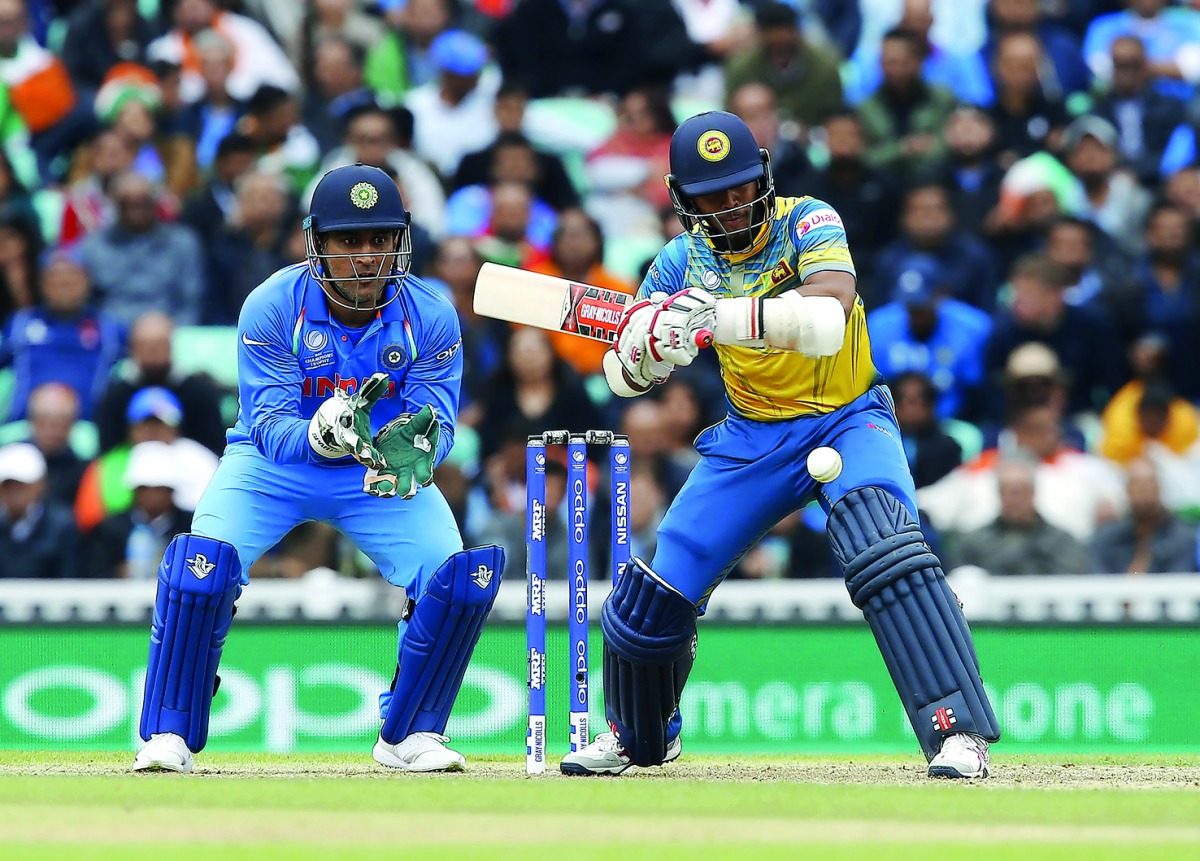 Sri Lanka's Kusal Mendis (right) hits a shot watched by India's MS Dhoni during the match.