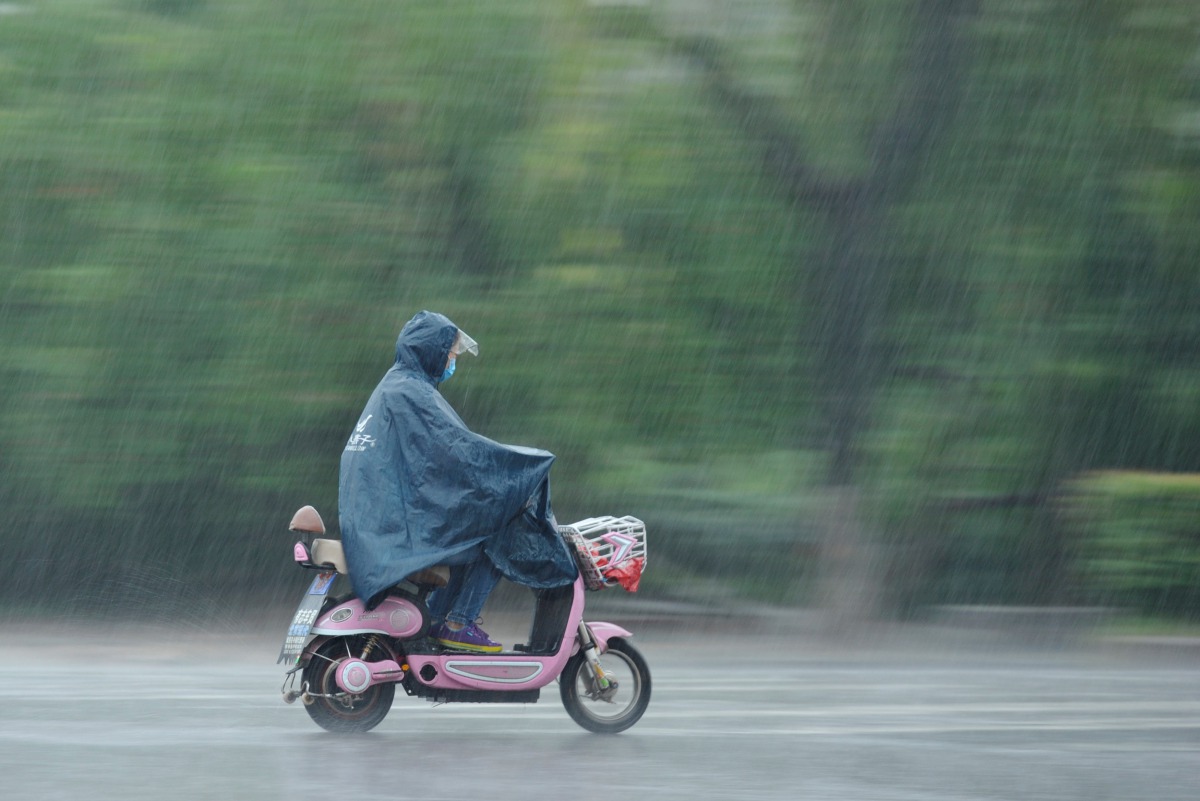A woman rides an electric scooter in heavy rain in Fuyang, Anhui province, China June 10, 2017. (REUTERS)