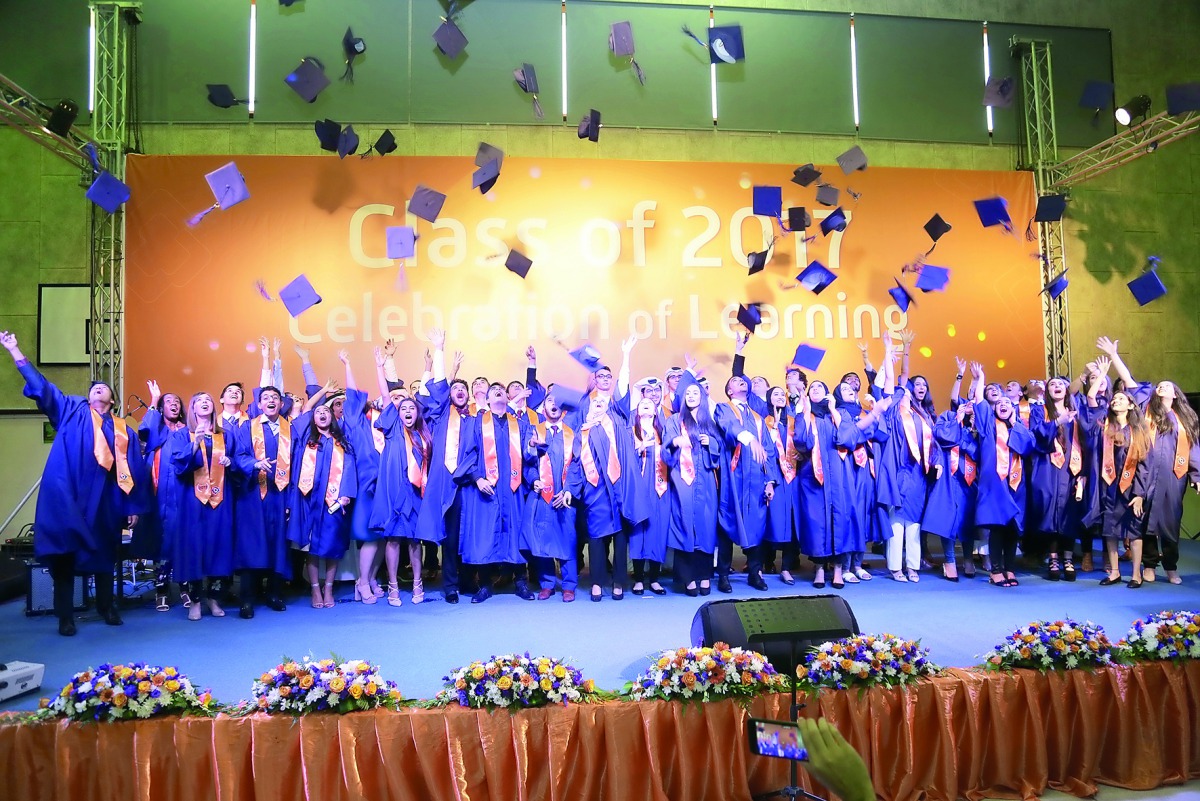 Graduates tossing hats in air during the graduation ceremony at ISL Qatar. 