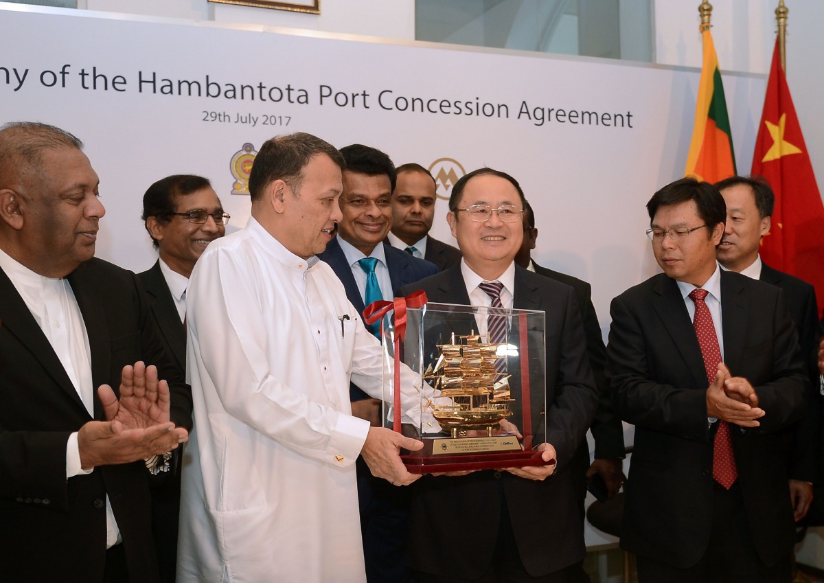 Sri Lanka's Minister of Ports & Shipping Mahinda Samarasinghe (C) exchanges souvenirs with Executive Vice President of China Merchants Port Holdings Dr. Hu Jianhua (3R) during the Hambantota International Port Concession Agreement at a signing ceremony in