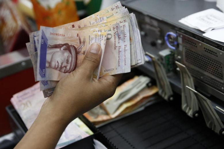 A cashier counts Venezuelan bolivar notes in a state-run supermarket in Caracas, January 9, 2015 (REUTERS / Carlos Garcia Rawlins) 