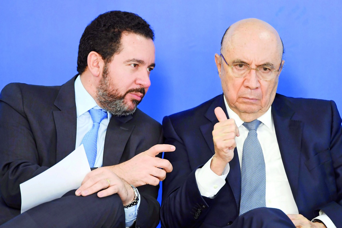 Brazilian Finance Minister Henrique Meirelles (R) listens to Planning Minister Dyogo Oliveira during the announcement of the distribution of the results of the workers' severance guarantee fund (FGTS) at the Planalto Palace in Brasilia, Brazil, on August 