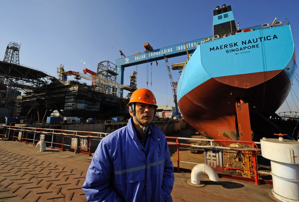 (FILES) This file photograph taken on February 15, 2008, shows a worker stands in front of an under-construction 300,000-tonne oil tanker for Danish shipping company Maersk and an under-construction offshore drilling platform at a shipyard in northeast Ch