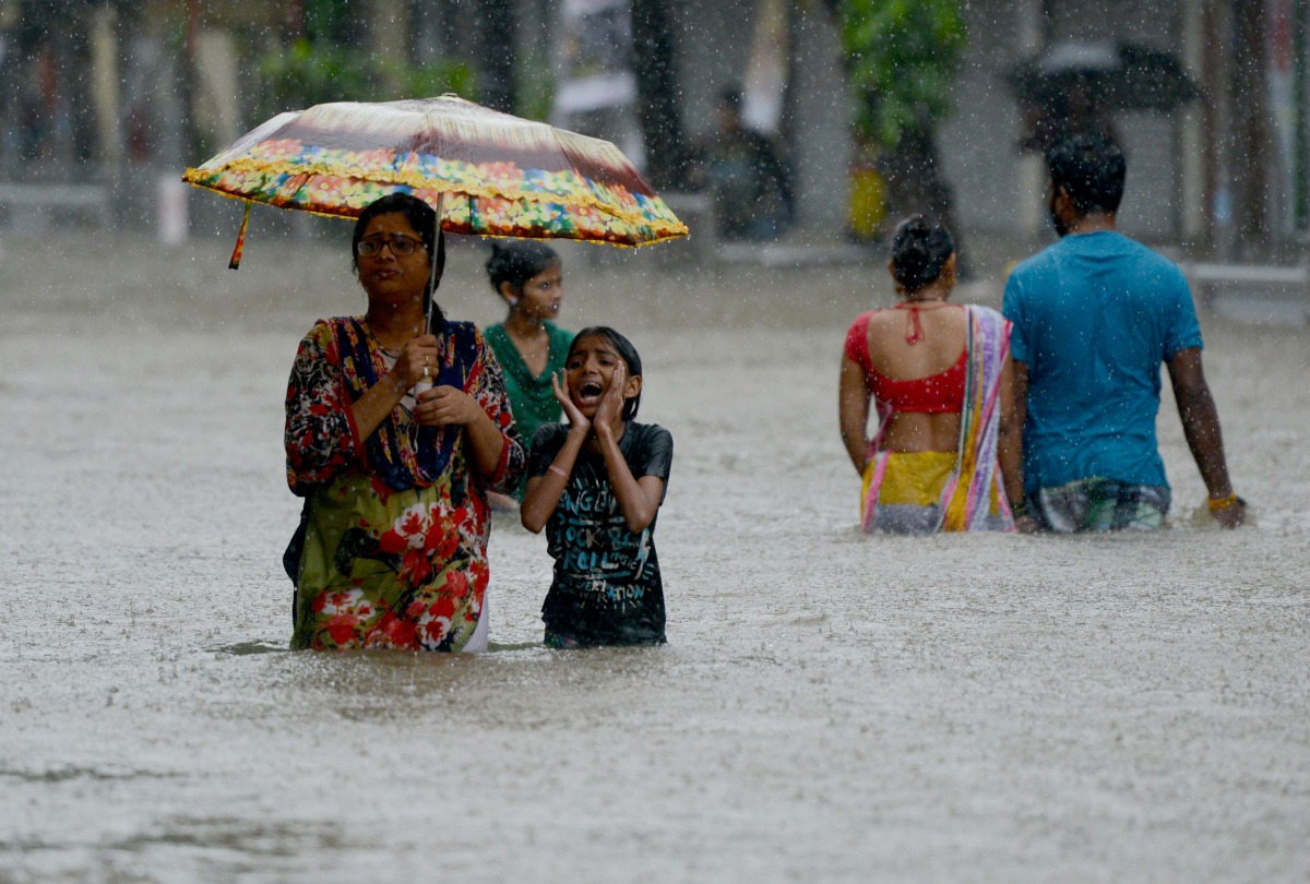 Indians wade through a flooded street during heavy rain showers in Mumbai on August 29, 2017.  AFP / Punit Paranjpe
