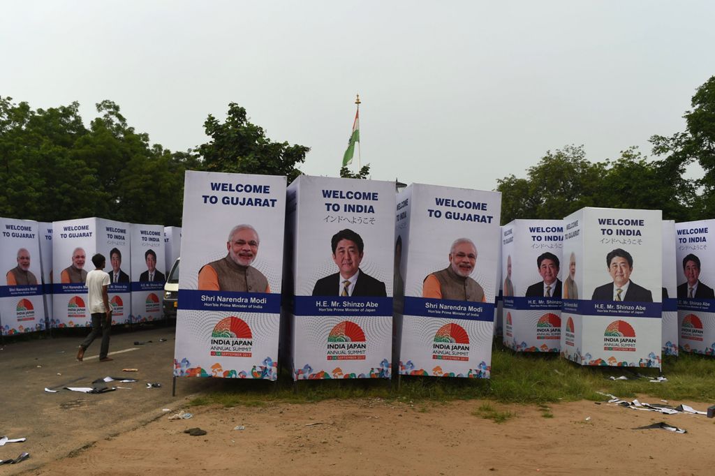 An Indian worker walks past poster witht the picture of Japanese Prime Minister Shinzo Abe and his Indian counterpart Narendra Modi, in Ahmedabad on September 10, 2017.  / AFP / SAM PANTHAKY