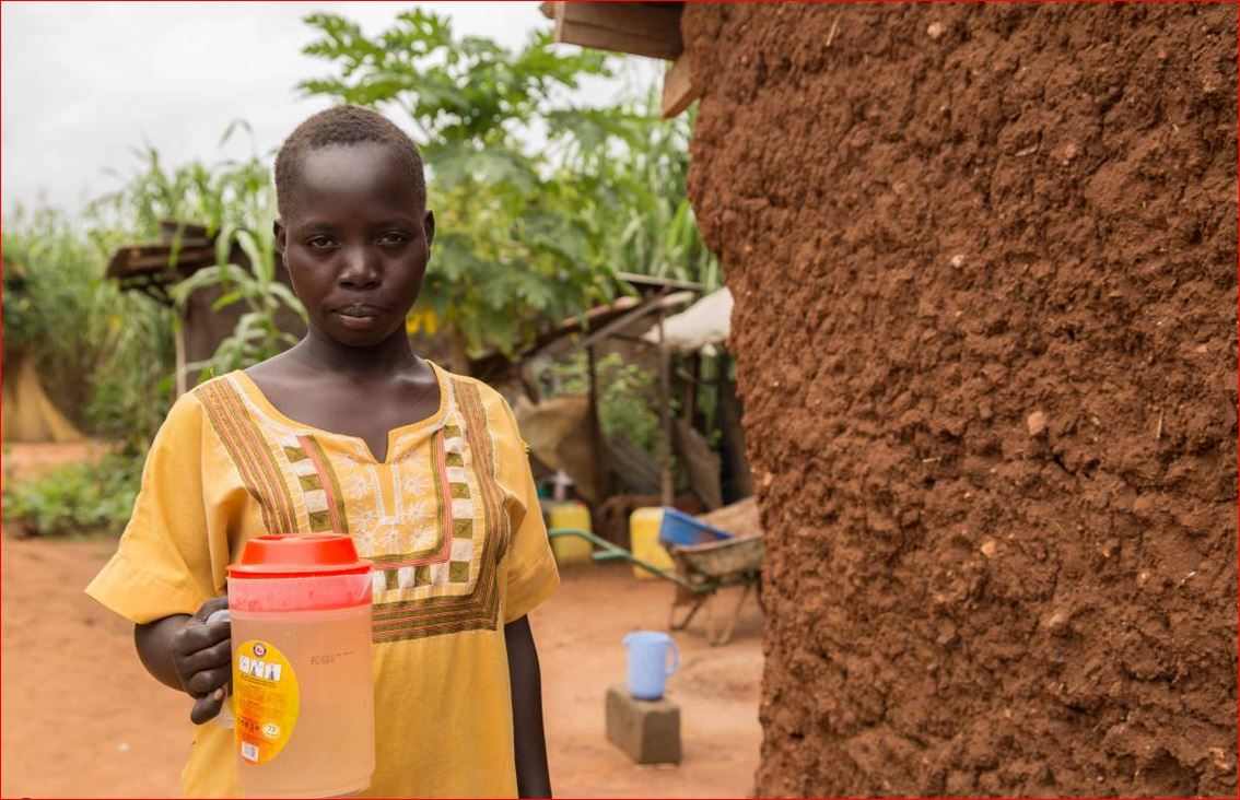 Mary, 18, shows the kind of yellow, muddy water that she and her family drink in Khor William, South Sudan, September 15, 2017. Thomson Reuters Foundation/Stefanie Glinski
