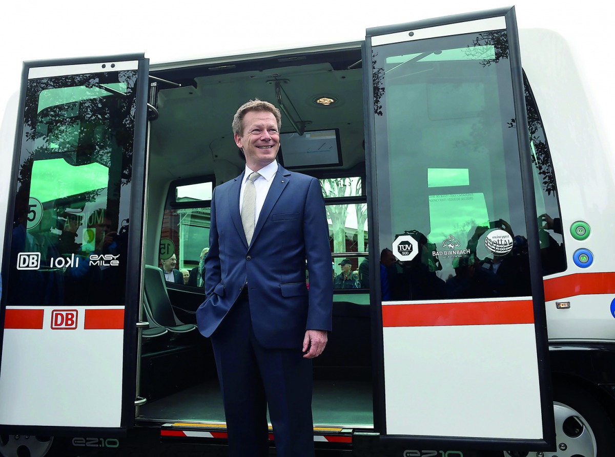 Richard Lutz, CEO of German railway company Deutsche Bahn, waves in front of the first German autonomous public transport bus during a presentation in Bad Birnbach, southern Germany, on October 25, 2017. AFP / Christof Stache