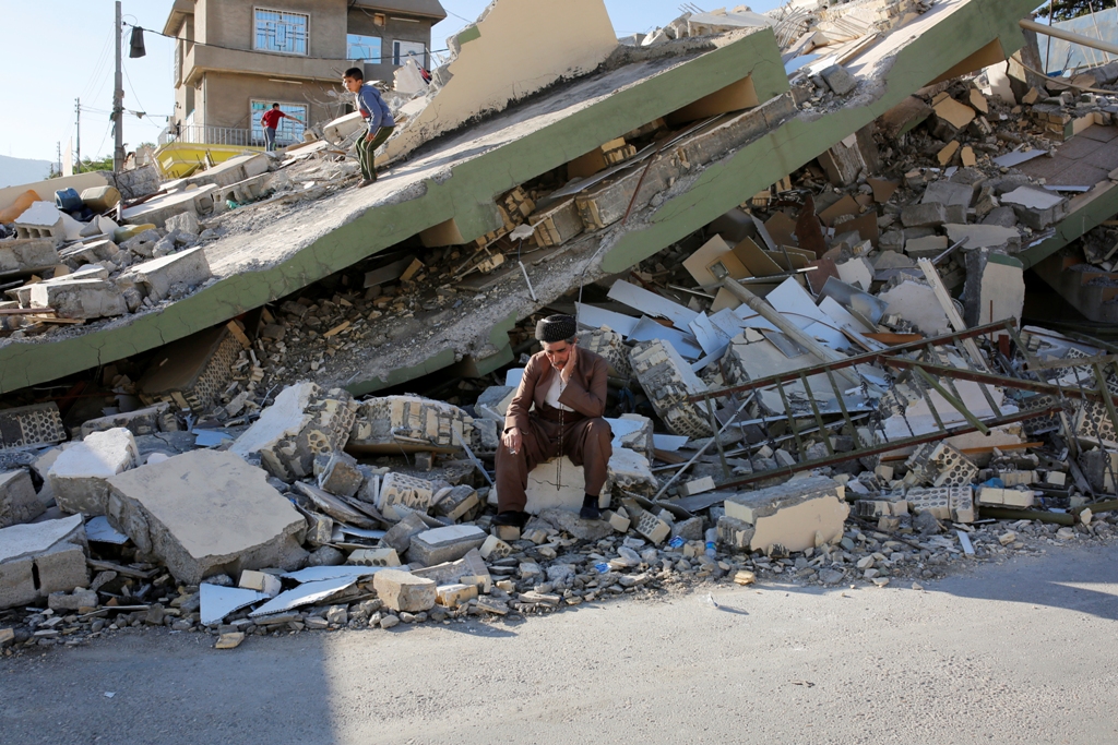 (file photo) A man sits on a concrete in front the collapsed building at Derbendihan district of Sulaymaniyah, in Iraq on November 13, 2017 following the 7.3 magnitude earthquake that hit the Iraq and Iran.  Yunus Kele? - AA 
