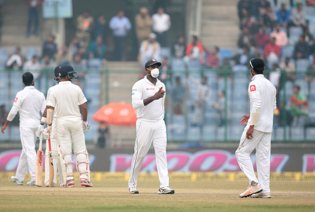 Sri Lankan player, wearing a face mask, gestures as he walks in the field. REUTERS/Stringer