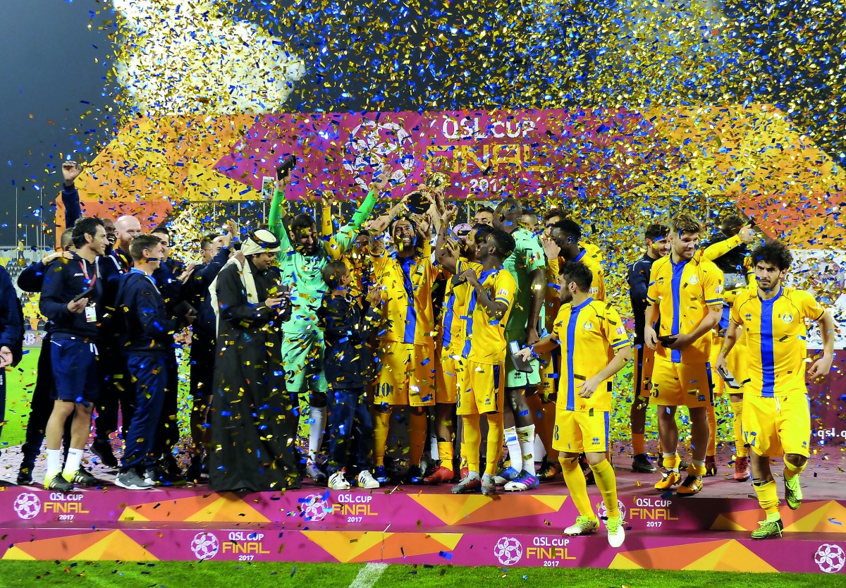 Al Gharafa players and officials celebrate after receiving the QSL Cup Trophy at Qatar SC Stadium yesterday. Pictures: Abdul Basit / The Peninsula