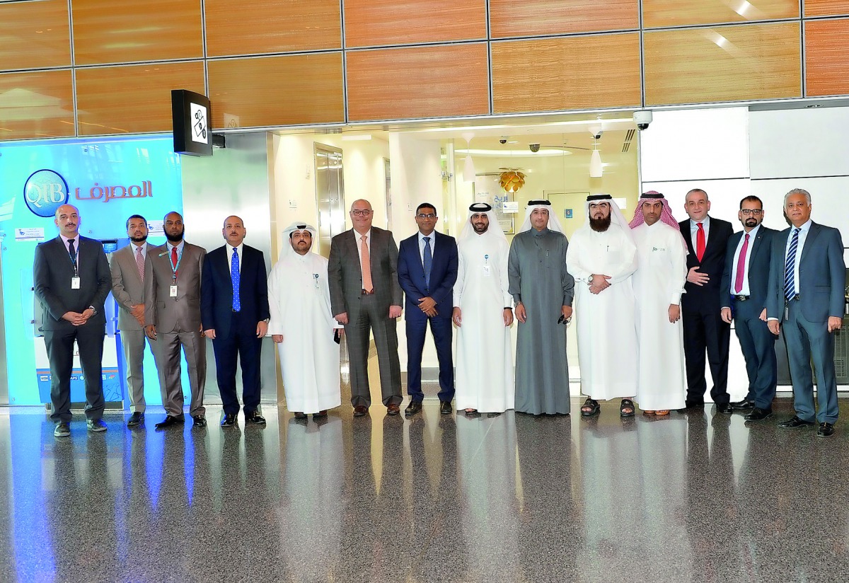 QIB officials pose in front of the Hamad International Airport branch of the bank.