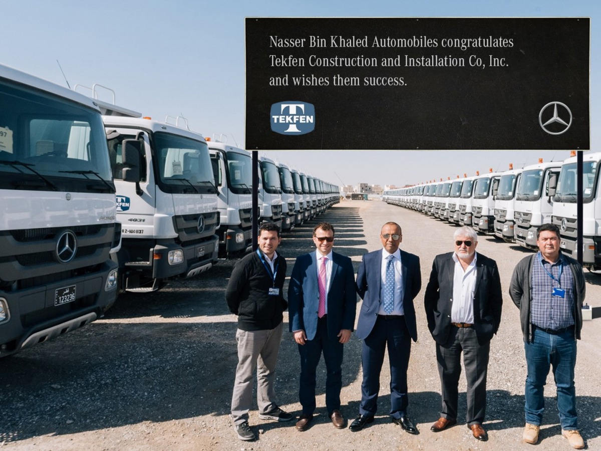 Senior officials from NBK and Tekfen posing with a fleet of Mercedes-Benz Actros trucks.