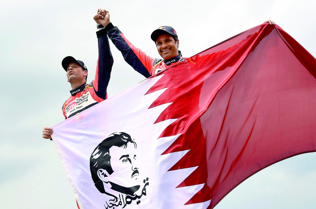 Qatari Rally Driver Nasser Saleh Al Attiyah (right) celebrating with Qatar’s flag after claiming the runner-up spot of the 40th Dakar Rally, held in Peru, Bolivia and Argentina, yesterday.