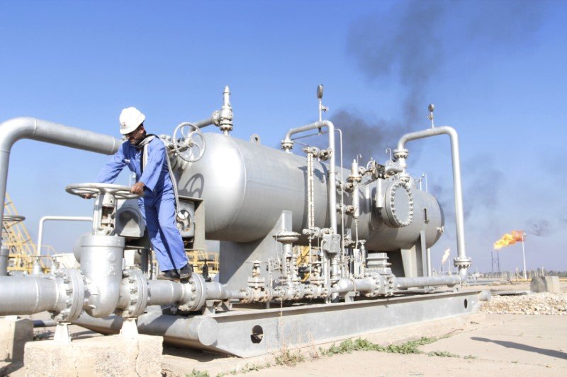FILE PHOTO: A worker checks the valve of an oil pipe at Nahr Bin Umar